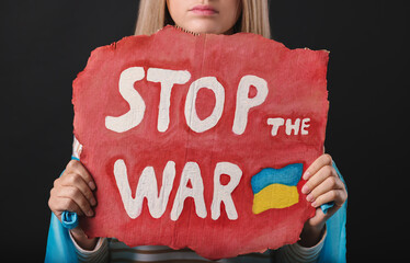 Poster - Sad woman holding poster with words Stop the War on black background, closeup