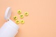 Bottle and yellow antidepressant pills with happy faces on pale orange background, flat lay. Space for text