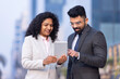 © G-images - Indian businessman and businesswoman using digital tablet on city street