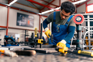 A worker works in a metal workshop, uses a hammer to straighten a metal bar; use protective equipment