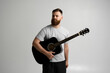 © Volodymyr - Portrait of handsome young bearded musician, guitar player standing with acoustic guitar and ready to play a music.