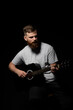 © Volodymyr - Portrait of handsome young bearded musician, guitar player plays a song with on a acoustic guitar in dark room.