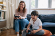 © cherryandbees - Mother and son playing video games at home