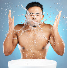 Canvas Print - Water splash, facial and man in studio for skincare, wellness and grooming on blue background. Cleaning, beauty and moisture by Mexican model relax with luxury, routine and face treatment isolated