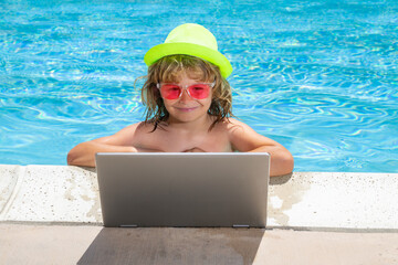 Wall Mural - Child working on laptop computer at swimming pool. Summer online technology. Traveler relaxing on tropical water in summer holidays vacation. Travel trip, kid using laptop.