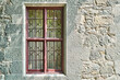 Old windows with wrought iron grating on stone wall of historical building. Medieval castle with restored walls attracts arriving visitors attention