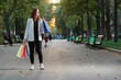 Full-size photo of young woman with paper shopping bags in the park. Successful shopping. Discounted sales.