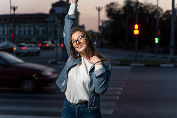 Sexy stylish young woman in glasses on evening city street background, summer time. Young pretty girl walk in city