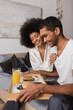 © LIGHTFIELD STUDIOS - happy african american man holding tray with pancakes and drinks near sexy girlfriend in bedroom
