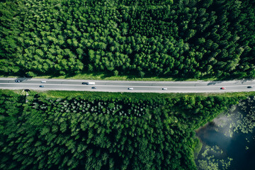 Wall Mural - Aerial view of road with cars through green summer woods by blue water lake in Finland.
