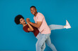 © Drobot Dean - Excited positive afro couple dancing isolated over blue background