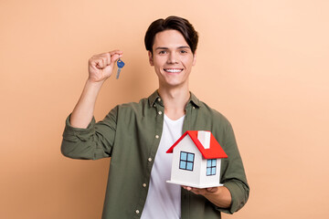 Wall Mural - Photo of young apartments cheerful guy hold new property keys house owner enjoy his quality loan good mood isolated on beige color background