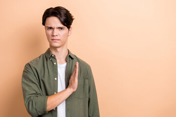 Sticker - Photo of serious handsome dissatisfied guy with brunet hair dressed khaki shirt palm showing stop deny isolated on beige color background