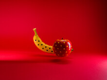 Close-up Of An Apple And Banana Painted With Polka Dots Against A Red Background