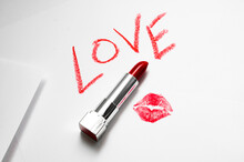 Love Text With Red Lipstick Kiss On White Background With Kiss. The Word LOVE Written In Lipstick On A White Background, Top View. The Concept Of Valentine's Day February 14