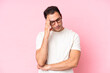 Young caucasian man isolated on pink background with headache