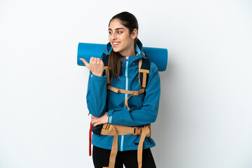 Wall Mural - Young mountaineer man with a big backpack over isolated background pointing to the side to present a product