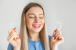 © Ivan - A young smiling woman holding invisalign braces over white background studio, dental healthcare and Orthodontic concept.