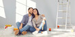 © Studio Romantic - What lovely modern home. Happy young family couple doing renovations inside new house. Tired but satisfied man and woman sitting on floor with paint bucket, hugging and looking at result of their work
