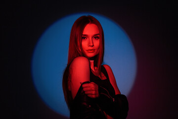 Stylish studio color creative female portrait of a beautiful stylish woman in fashionable clothes with red light on a dark background