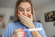 © Ivan - Happy smiling woman looking at pregnancy test at home. Pregnancy, fertility, maternity, emotions and people concept .