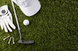 White visor, glove, three tees, golf ball and golf club on grass with copy space