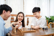 © DG PhotoStock - Happy Asian lovely family staying and playing a chess game together in living room in weekend, Group of Asian people playing chess game together in.