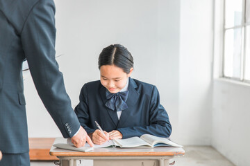 学校・塾で個別指導・マンツーマン指導する中学生・高校生・小学生と先生・教師・塾講師（笑顔）
