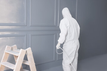 Poster - Decorator dyeing wall in grey color with spray paint indoors, back view