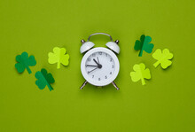 St.Patrick 's Day. Paper-cut Clover Leaves With Alarm Clock On A Green Background. March 17. Flat Lay. Top View