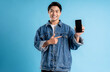 Young asian man using phone on a blue background