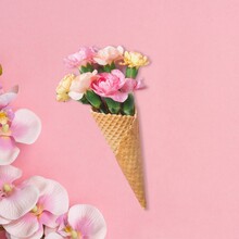 Flat-lay Of Waffle Sweet Cone With Flowers Over Pastel Light Pink Background, Top View. Spring Or Summer Mood Concept