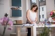 © Cavan Images - Pregnant woman folding baby clothes in the kitchen, Munich, Bavaria, Germany