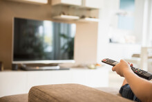Woman watching TV with remote control in her hand, Munich, Bavaria, Germany
