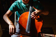 © Cavan Images - Close-up of boy sitting in bright patch of light practicing cello