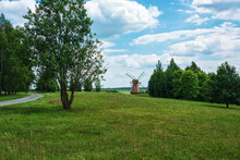 Summer Landscape. Old Wooden Mill In The Distance And Green Trees