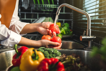 Hand of maid washing tomato fresh vegetables preparation healthy food in kitchen