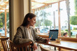 © Evrymmnt - Portrait of young beautiful woman having a video call on her phone in a coffee shop. Remote work concept. Female freelancer working in coffeehouse, checking her phone. Close up, copy space, background