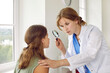 © Studio Romantic - Female doctor examining child's skin. Professional dermatologist in white coat uses magnifying glass to investigate and diagnose some growth on face of teenage girl. Dermatology, skin health concept