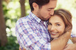© Jeff B/peopleimages.com - Happy couple hug, bonding or forehead kiss on love date, valentines day or romance nature break, park or relax garden. Woman, smile or man kissing head in trust, security embrace or thank you support