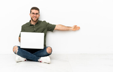 Poster - Young man sitting on the floor extending hands to the side for inviting to come