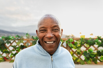 Happy senior African man smiling in front of camera on house patio