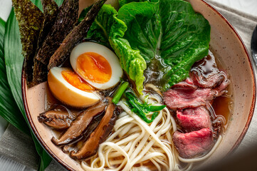 Wall Mural - Asian ramen soup with rice noodles, mushrooms and pork in black bowl. Asian cuisine.