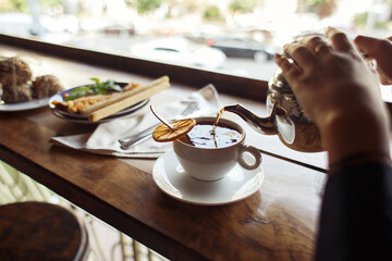 black tea is poured into the cup with orange on the breakfast table outdoor. healthy concept High quality photo