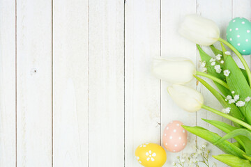 Poster - Pastel Easter eggs and white spring tulip flowers. Top view side border against a white wood background. Copy space.