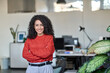© insta_photos - Young smiling latin professional business woman confident leader, happy female company executive, beautiful lady sales manager standing in modern office with arms crossed, looking at camera, portrait.