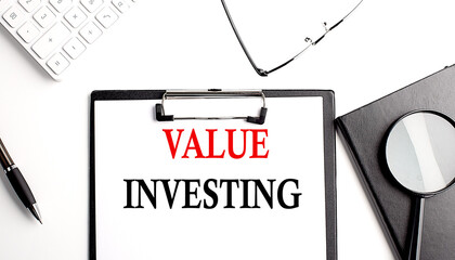 Poster - VALUE INVESTING text written on paper clipboard with office tools