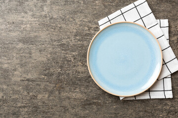 Sticker - Top view on colored background empty round blue plate on tablecloth for food. Empty dish on napkin with space for your design