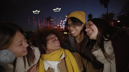 Wall Mural - Group of four cheerful young friends taking selfie in winter clothes at night. Happy people looking at each other and at the camera smiling. Concept of youth lifestyle. Tourist on vacation.