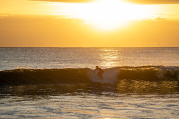 Wall Mural - Silhouette surfer catching a wave at sunrise